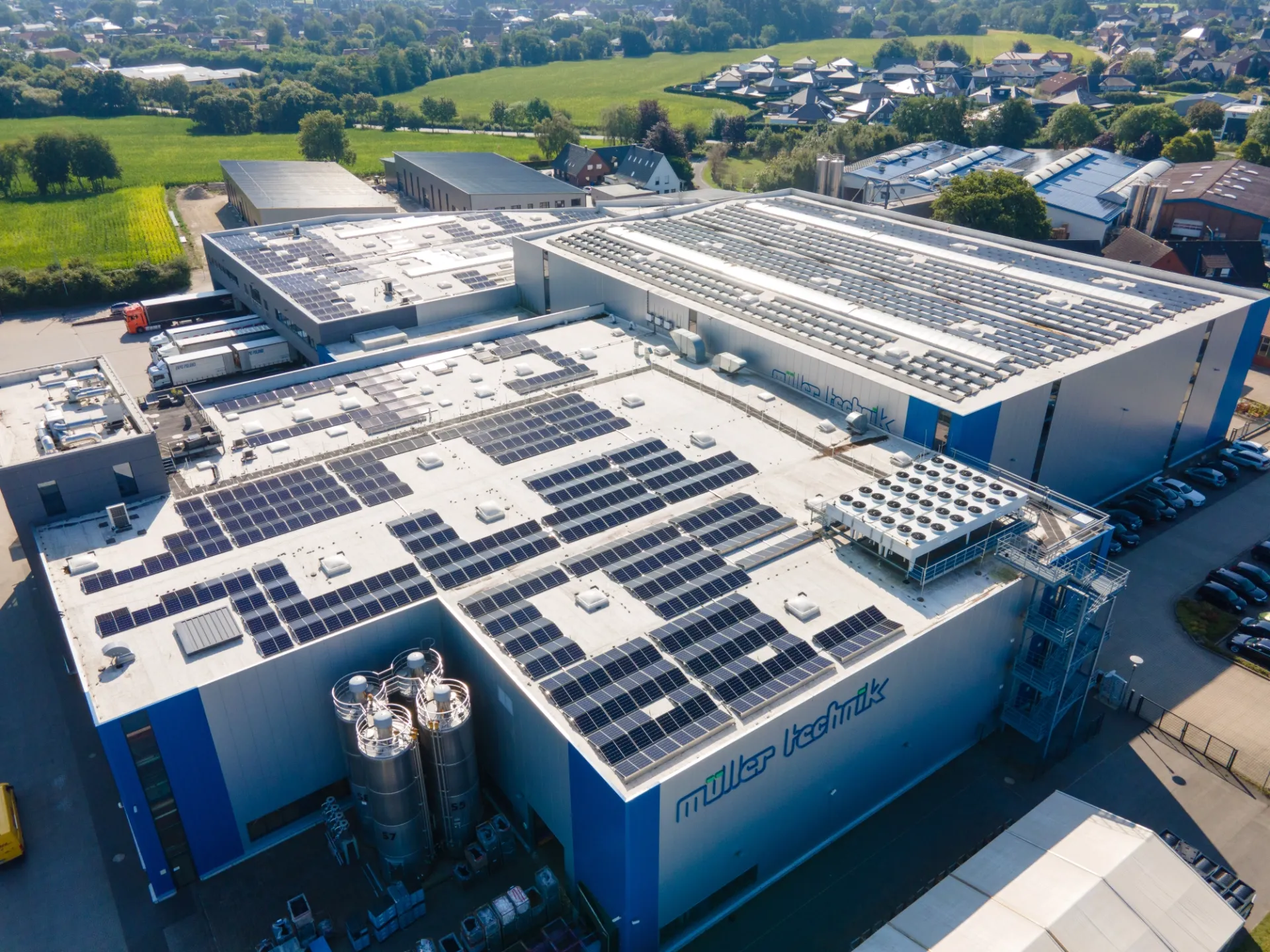Luftaufnahme des Hauptgebäudes von Müller Technik mit Fokus auf die installierten Photovoltaikanlagen auf dem Unternehmensdach